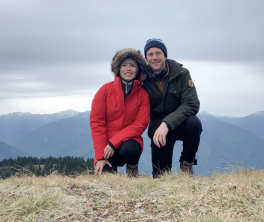 John Kreckel on a hike, mountains and clouds in the background