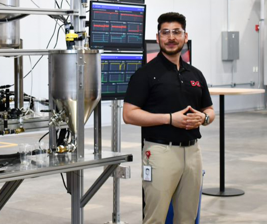 Photo of Rodrigo Perez on the factory floor with computer monitors behind him