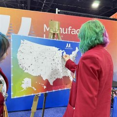 Photo of student with green hair placing a pin on a map at Manufacturing USA's SkillsUSA booth