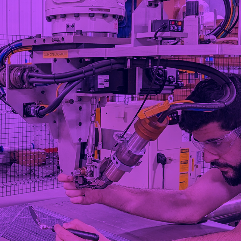 Photo of a male leaning over a work table with machine.