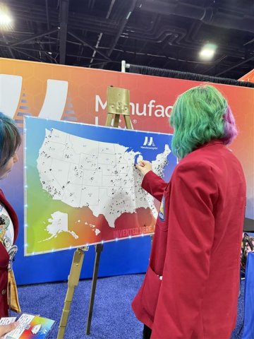 Photo of student with green hair placing a pin on a map at Manufacturing USA's SkillsUSA booth