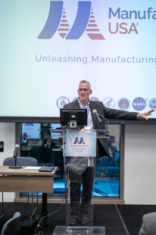 Gregg Bartlett stands at a podium at the 2025 Manufacturing USA Network Meeting