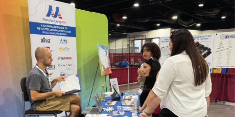 Photo of a Manufacturing USA representative talking to attendees at the Manufacturing USA booth at SkillsUSA 2025